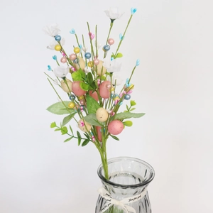 Detailed view of Easter egg floral stems with speckled eggs and white berries in a glass vase