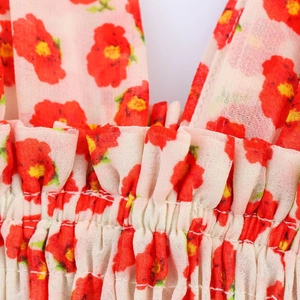 Detail van rode bloemenprint jurk met elastische taille en ruches aan de rand
