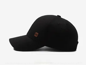 Detail of black baseball cap side with KWC brown leather patch and woven texture
