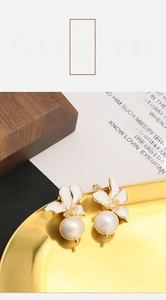 Detailed close-up of white flower earrings with zircon centers and hanging pearls