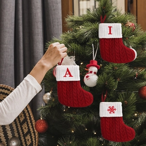 Knitted Christmas stockings with red cable knit and white cuffs hanging on a festive tree