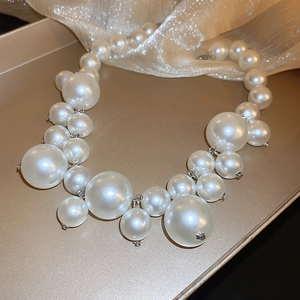 Detailed view of glossy white pearls connected by silver metal rings on silk fabric