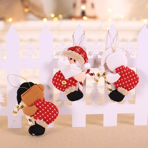 Three plush Christmas dolls including Santa and bear hanging on a white wooden fence