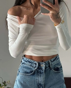 Detail eines weißen schulterfreien Oberteils kombiniert mit blauer High-Waist-Jeanshose