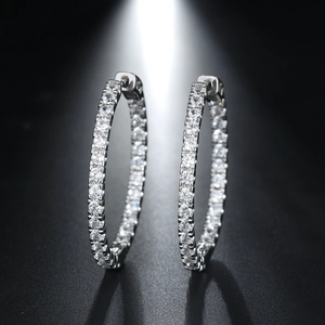Macro shot of silver hoop earrings with shimmering CZ stones on black background