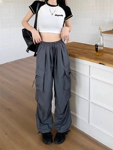 Detail of dark grey cargo pants with adjustable drawstring cuffs and functional pockets