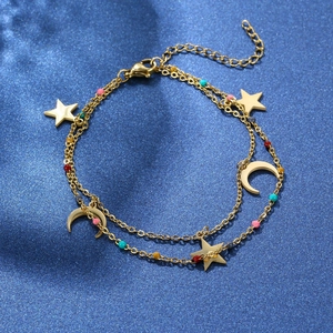 Detail of gold layered bracelet with colorful beads and star moon charms on blue silk