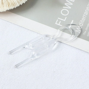 Close-up of transparent plastic U-shaped hair pins for bun styling on white textured fabric