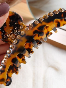 Macro detail of tortoiseshell hair claw clip with inlaid brown rhinestones and resin finish