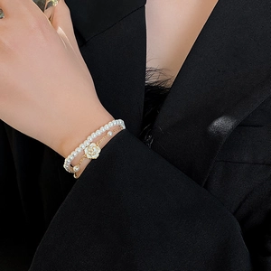 Detail of camellia pearl bracelet featuring white floral charms and gold metal layers