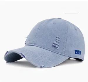 Detail of distressed light blue denim baseball cap with 1999 blue embroidery
