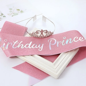 Detail of pink glitter Birthday Princess sash and silver rhinestone crown on white frame