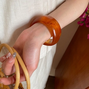 Detail of amber tortoiseshell resin bangle showing natural translucent texture on wrist