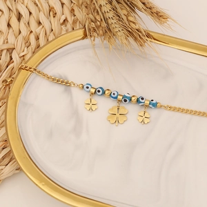 Golden Evil Eye bracelet with clover charms displayed on a marble jewelry tray