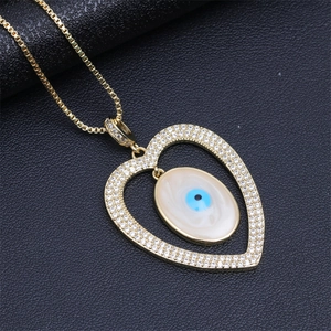 Macro view of gold heart pendant with evil eye motif and pavé cubic zirconia inlay
