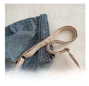 Close-up of beige corduroy tote bag featuring adjustable wide strap and metal buckle