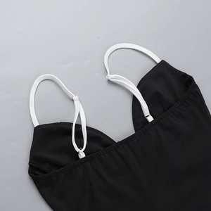Detalle del cuello en V y finos tirantes blancos en un vestido ajustado negro
