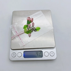 Detail showing handmade glass cherry beaded phone charm on a scale weighing 4.2g