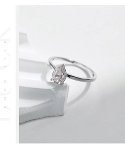 Detail of pear-cut moissanite ring in S925 silver on white geometric background