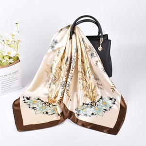 Detailed texture of beige floral satin scarf draped over a black handbag