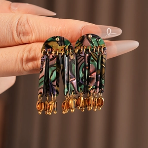 Close-up of bohemian shell tassel earrings with iridescent finish and golden metal parts