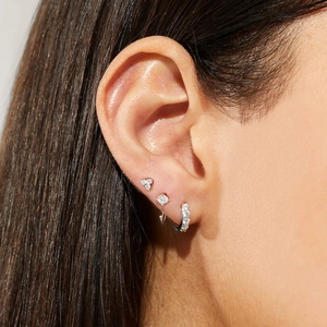 Close-up of three-piece silver jewelry set with sparkling zircons on female ear lobe
