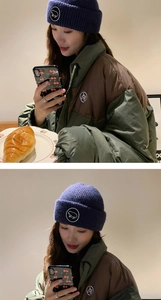 Détail du bonnet en maille bleu marine avec un écusson brodé en forme de grenouille