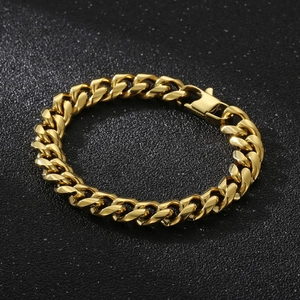 Macro shot of polished gold Cuban link bracelet on a textured black background