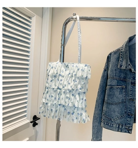 Close-up of white lace mesh shoulder bag with blue floral patterns and tiered ruffles