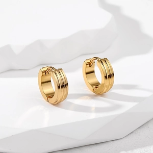 Close-up of gold stainless steel huggie earrings with three parallel engraved lines