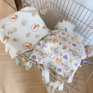 Détail de sacs cabas en coton avec imprimés fleurs et ours dans un chariot en métal