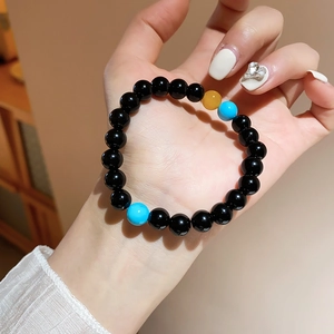 Detail of beaded bracelet with black agate stones, turquoise and amber accents on wrist