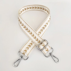 Close-up of adjustable beige nylon strap with golden arrow pattern and silver hardware