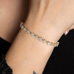 Detail of a thin gold tennis chain with cubic zirconia worn on a woman's wrist
