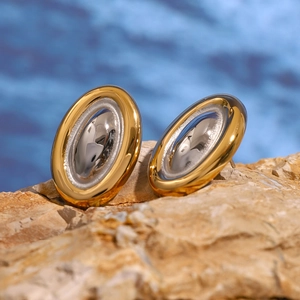 Boucles d'oreilles ovales bicolores dorées et argentées sur un fond de roche naturelle