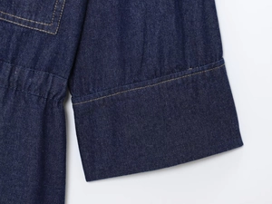 Close-up of dark blue denim sleeve and waist detail with yellow contrast stitching