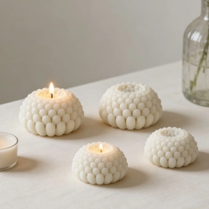 Dettaglio di candele succulente bianche a perle con texture satinata su lino