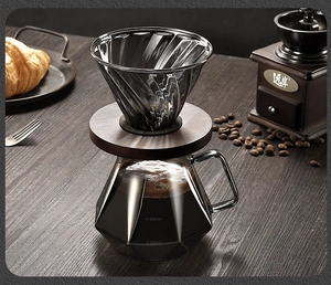 Detailed view of the diamond-shaped glass coffee server with capacity scales and wood stand