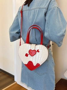 White heart-shaped crossbody bag with red arrow decor and crocodile texture on model