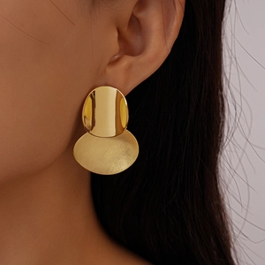 Close-up of geometric oval drop earrings with mixed polished and brushed gold finish
