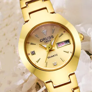 Détail macro de montre dorée pour femme avec index en zircon et guichet jour-date