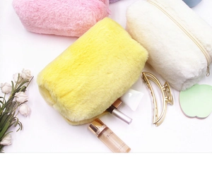 Vista dall'alto di trousse in peluche colorate in rosa, viola, giallo e bianco soffice
