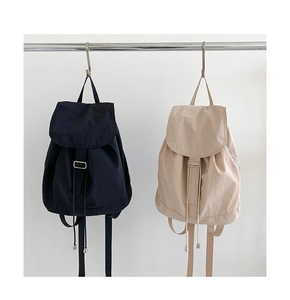 Dettaglio dello zaino in nylon con opzioni di colore nero e beige in uno stile minimalista