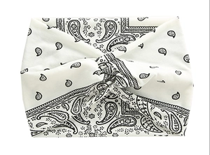 Detail of wide ivory paisley headband with cross twist design and vintage pattern