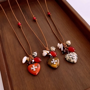 Détails de pendentifs cœur en pierre et perles de bois sur colliers ethniques tressés