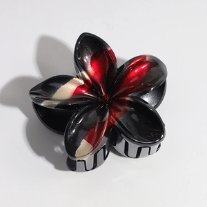Detail of lily hair claw clip with black and red gradient finish and golden edges