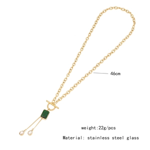 Detail of a gold stainless steel necklace with green square and clear teardrop glass charms