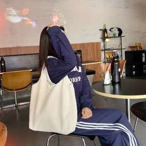 Lifestyle view of large beige canvas tote bag shown by a model in a cafe setting