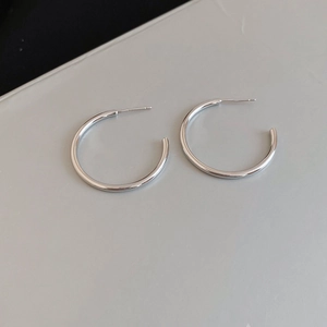 Macro shot of minimalist silver round hoop earrings featuring a high-polish metallic finish