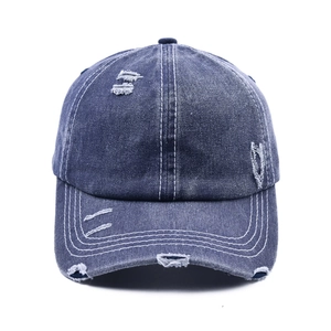 Detail of distressed navy denim baseball cap with vintage worn-out holes and white stitching